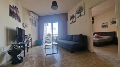 a living room with a blue couch and a bed at Serenity by the sea in Larnaka