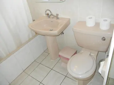 a white bathroom with a toilet and a sink at Tsialis Hotel Apartments in Larnaka