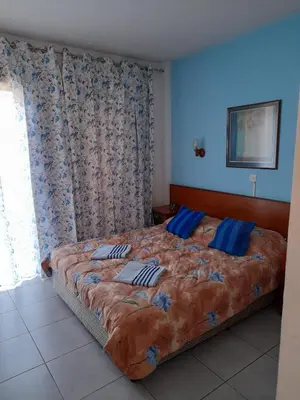 a bedroom with a large bed with blue walls at Onisillos Hotel in Larnaka