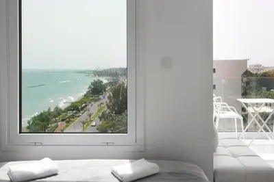 a bedroom with a large window overlooking the ocean at The White Pearl Suite - beach front city centre with sea view. in Limassol