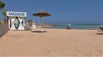 a sandy beach with an umbrella and a massage at Villa Kiveli in Ayia Napa