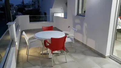 a white table and four red chairs on a balcony at CHRIS'S HOLIDAY APT - AYIA NAPA in Ayia Napa