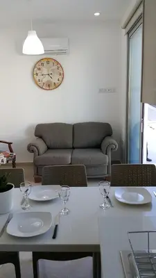 a table with wine glasses and a clock on the wall at CHRIS'S HOLIDAY APT - AYIA NAPA in Ayia Napa