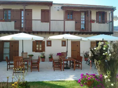 a patio with tables and umbrellas in front of a building at Charalambos Holiday Cottage in Kalavasos