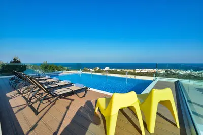 a group of chairs and a swimming pool on a deck at Aetopetra Villa in Protaras