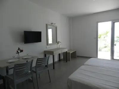 a bedroom with a bed and a table and a mirror at Evabelle Napa Hotel Apartments in Ayia Napa