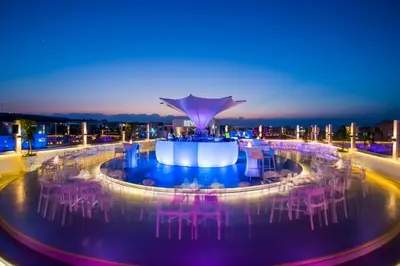 a view of a pool with pink chairs at night at Protaras Plaza Hotel in Protaras