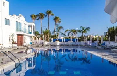 a swimming pool with chairs and palm trees at Protaras Plaza Hotel in Protaras