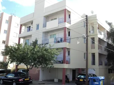 a white building with cars parked in front of it at Lykavitos Apartments in Nicosia