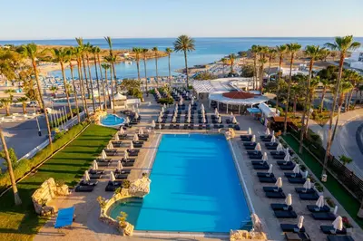 an aerial view of a resort with a pool and palm trees at Pavlo Napa Beach Hotel in Ayia Napa