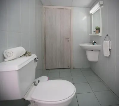 a white bathroom with a toilet and a sink at Pier Beach Hotel Apartments in Limassol