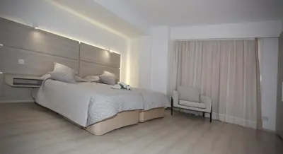 a bedroom with a large bed and a chair at Pier Beach Hotel Apartments in Limassol