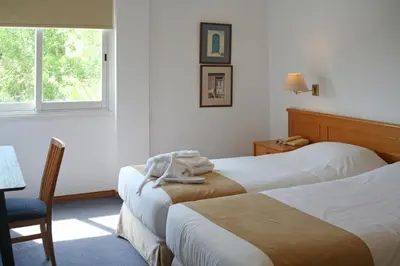 a hotel room with two beds and a chair and a window at Chrielka Hotel in Limassol