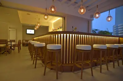 a restaurant with a bar with white stools at Sunrise Gardens Aparthotel in Protaras