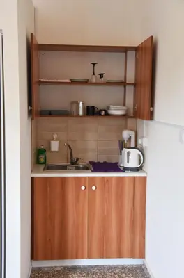 a small kitchen with wooden cabinets and a sink at Lucky 4 in Paralimni
