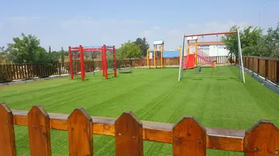 a playground with a large grassy field with a wooden fence at BG06 Mythical Sands in Paralimni