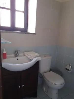 a white bathroom with a toilet and a sink at Vrakas House in Tochni