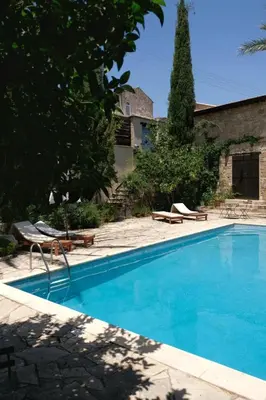 a blue swimming pool with two lounge chairs and a house at Porfyrios Country House in Chirokitia