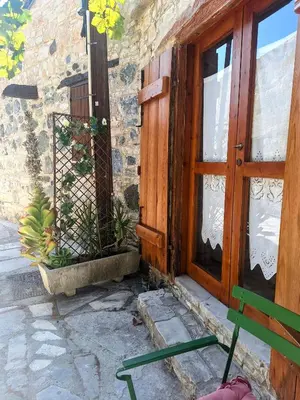 a wooden door and a bench next to a building at Eleni's Cottage in Apsiou