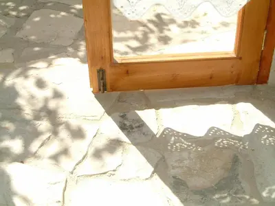 a wooden door with a shadow on the ground at Eleni's Cottage in Apsiou