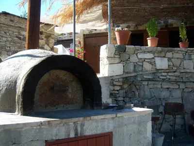 an outdoor pizza oven with a stone wall at Eleni's Cottage in Apsiou