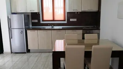 a kitchen with a wooden table and a refrigerator at Agrino Hotel Apartments in Ayia Napa