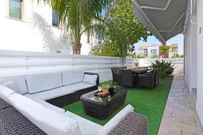 a patio with white couches and a table and chairs at Villa Calliopi in Protaras