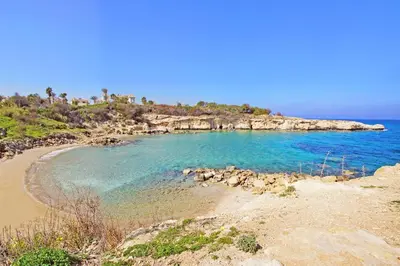 a beach with blue water and a rocky island at Villa Calliopi in Protaras