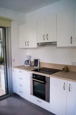 a kitchen with white cabinets and a stove top oven at Idyllic studio with private pool in Nicosia