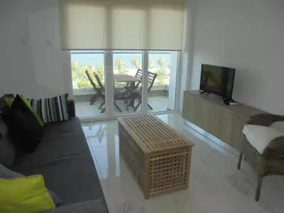 a living room with a couch and a television and a table at Kermia Court - Beach-front, modern 2 bedroom -sleeps 6 in Limassol