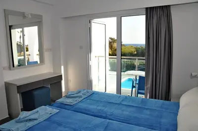 a bedroom with a blue bed and a balcony at Kaos Hotel Apartments in Ayia Napa
