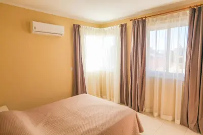 a bedroom with a bed and a window with curtains at Carisa Livadia Gardens in Livadhia