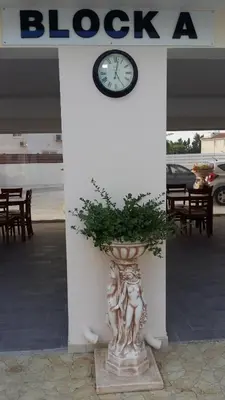 a plant in a vase in front of a building with a clock at Carisa Livadia Gardens in Livadhia