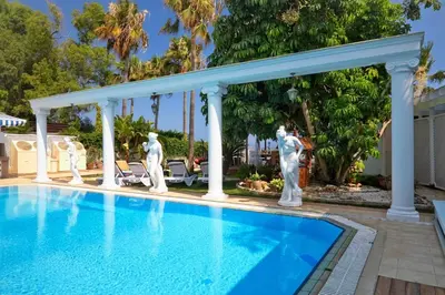 a swimming pool with statues next to a house at Limassol Beachfront Holiday Villa in Limassol