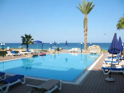 a large swimming pool with chairs and a palm tree at one bedroom apartment in Fig tree bay in Protaras