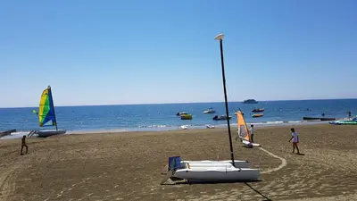 a boat on a beach with people on the sand at ZORBAS Sea View No 4 in Larnaka