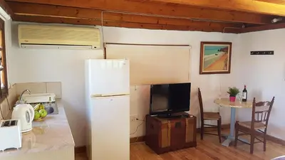 a kitchen with a refrigerator and a table with a tv at ZORBAS Sea View No 4 in Larnaka