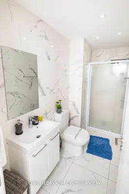 a white bathroom with a toilet and a sink at Lazuli City & Seaview Apartments in Larnaka