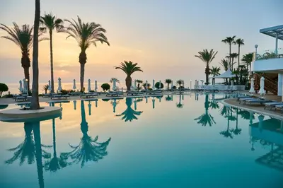 a swimming pool with palm trees in a resort at Sunrise Beach Hotel in Protaras