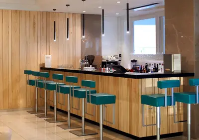 a kitchen with a bar with green stools at Sunrise Oasis Hotel & Waterpark in Protaras
