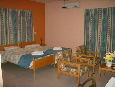 a bedroom with a bed and two chairs and a table at Rantzo Holiday Apartments in Pissouri