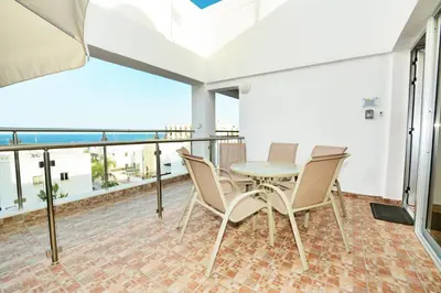 a balcony with a table and chairs and a view of the ocean at Seafront Protaras Apartments in Protaras