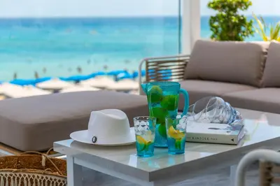 a table with a hat and glasses on a beach at Sunprime Protaras Beach - Adults Only in Protaras