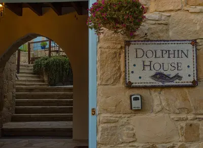 a sign for a dogin house on a stone wall at Dolphin Guest House and Studios in Tochni