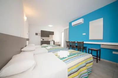 a hotel room with two beds and a kitchen at A Maos Hotel Apartments in Ayia Napa