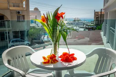 a vase with flowers on a table on a balcony at A Maos Hotel Apartments in Ayia Napa