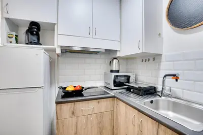 a kitchen with white cabinets and a bowl of fruit on the counter at Atlantis Apartments 50m from Makenzy seafront in Larnaka