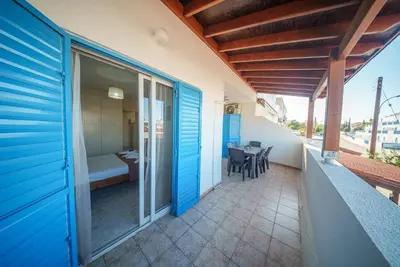 a balcony of a house with blue doors and a table at The Valley Beyond in Paralimni