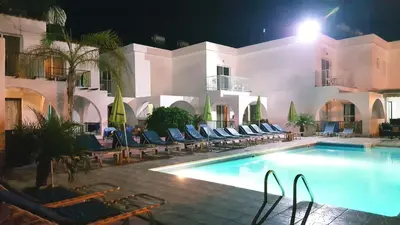 a swimming pool in front of a building at night at Florence Hotel Apartments in Ayia Napa