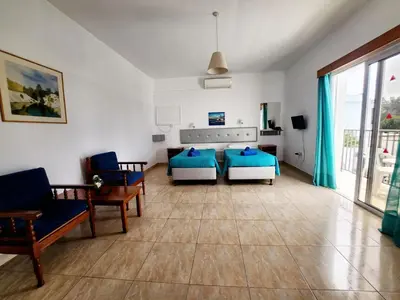a bedroom with a bed and a couch and chairs at Florence Hotel Apartments in Ayia Napa